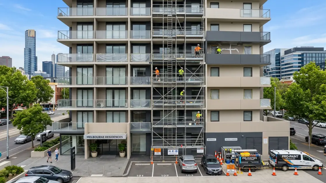 Commercial Painters Deanside | Office & Industrial Painting 7 Painters working on a multi-storey residential building using scaffolding to repaint facades and balconies.